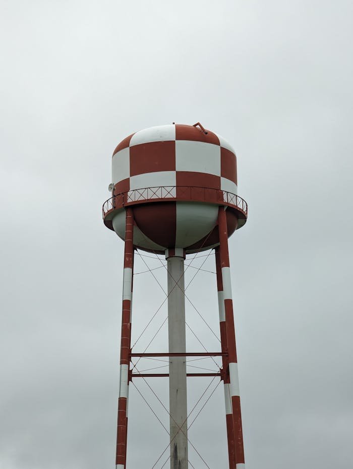 Vertical shot of a red and white checkered water tower against a cloudy sky in Canada.